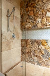 a shower in a bathroom with a stone wall at La Parcela Cunkal in Conkal