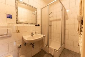 a white bathroom with a sink and a shower at Hotel Fronhof Mettendorf in Mettendorf
