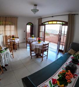 een woonkamer met tafels en stoelen en een balkon bij Pousada da Seresta in Diamantina