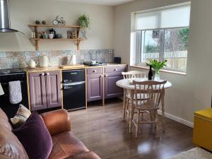 uma cozinha com armários roxos, uma mesa e cadeiras em Yew Fold em Soutergate