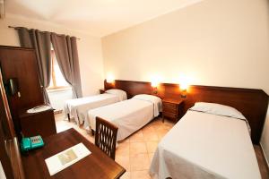ein Hotelzimmer mit 3 Betten und einem Tisch in der Unterkunft HOTEL VULCI in Montalto di Castro