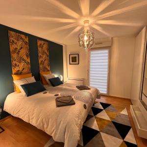 a bedroom with a large bed and a chandelier at Maison COMet avec jardin et parking in Orléans