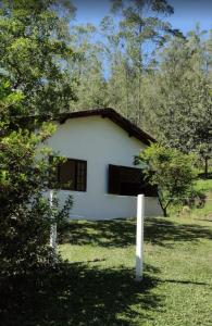 una casa blanca en medio de un campo en Casa de Campo no Parque Estadual da Serra do Mar, en São Luís do Paraitinga