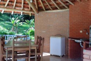a table and chairs and a refrigerator in a room at Casa de Campo no Parque Estadual da Serra do Mar in São Luiz do Paraitinga