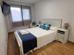 a bedroom with a large white bed with a window at Playa Jardin Boiro in Boiro