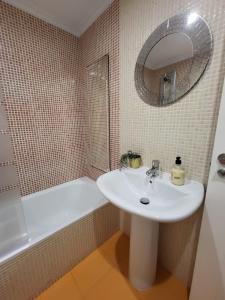 a bathroom with a sink and a tub and a mirror at Playa Jardin Boiro in Boiro