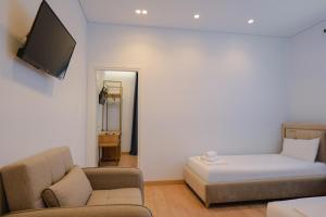 a room with a bed and a couch and a tv at Otto Hotel in Ksamil