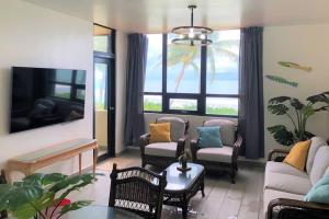 ein Wohnzimmer mit einem Sofa, Stühlen und einem TV in der Unterkunft Beachfront Getaway for two! in Humacao