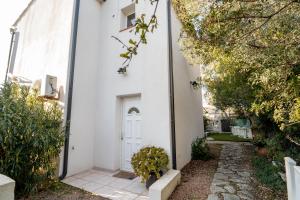 een wit huis met een witte deur en planten bij L'ALIVETTE in Bastelicaccia