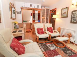una sala de estar con muebles blancos y almohadas rojas. en Chestnut Apartment, en Cheltenham