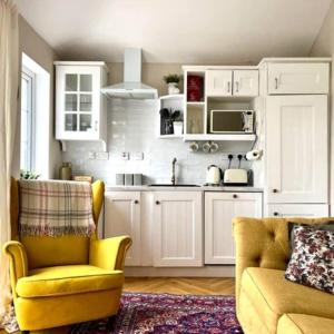 a kitchen with white cabinets and a yellow chair and a couch at Killenard Kottage, Killenard, Laois in Killenard
