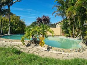 a swimming pool in a yard with palm trees at Sleepwell in East London