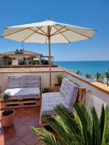 a patio with an umbrella and two chairs and a bed at Seafront apartment with rooftop terrace and pool in Calafell