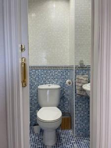 a bathroom with a toilet and a blue tiled wall at Seafront apartment with rooftop terrace and pool in Calafell