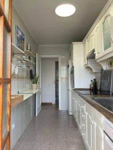 a large kitchen with white cabinets and a sink at Seafront apartment with rooftop terrace and pool in Calafell