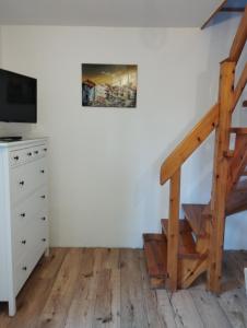 a room with a staircase and a dresser with a television at Liliomfa apartman in Szigliget