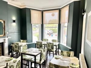 a dining room with tables and chairs and windows at Devon House Guest House in Paignton
