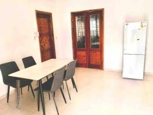 a dining room with a table and chairs and a refrigerator at Gloryphil House in Lomé