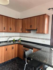 eine Küche mit Holzschränken und einer schwarzen Arbeitsplatte in der Unterkunft Apartamento El Mar in San Andres y Sauces