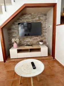 ein Wohnzimmer mit einem TV an einer Backsteinwand in der Unterkunft Casa Rural Villa Briar in Olvera