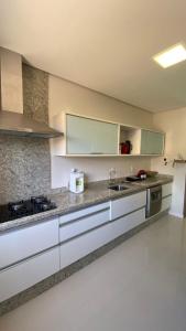 uma cozinha com armários brancos e uma bancada em Apartamento Costão das Gaivotas - Praia do Santinho - Ingleses - Florianópolis em Florianópolis