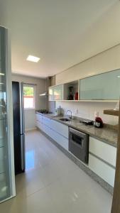 uma grande cozinha com balcões brancos e um lavatório em Apartamento Costão das Gaivotas - Praia do Santinho - Ingleses - Florianópolis em Florianópolis