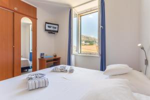 a bedroom with a large white bed with a window at Apartment& Room Lukre / Apartment Lukre with terrace in Dubrovnik