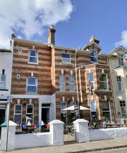 un edificio de ladrillo con mesas y sillas delante de él en Devon House Guest House, en Paignton