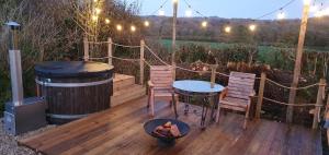 una terrazza con 2 sedie, un tavolo e una griglia di Forton House Shepherd's Huts a Chard