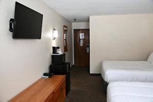 a hotel room with a bed and a flat screen tv at Hibbing Inn and Suites in Hibbing