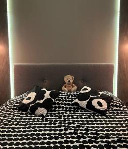 ein Teddybär auf einem Bett mit schwarzen und weißen Kissen in der Unterkunft New condo with free parking 10 min from Helsinki Airport in Vantaa