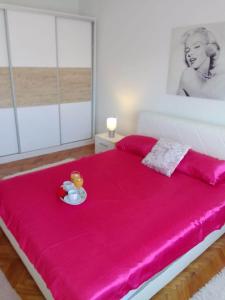 a pink bed with a plate of food on it at Holiday home Buljat in Kaštela
