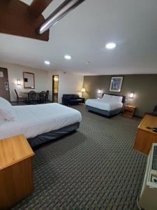 a hotel room with two beds and a living room at Hibbing Inn and Suites in Hibbing