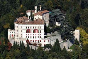 a large white castle on a hill with trees at Casa Angela a Follina in Follina