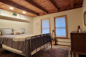 - une chambre avec un lit, 2 fenêtres et une guitare dans l'établissement Double deck treetop art chalet, à Stone Ridge