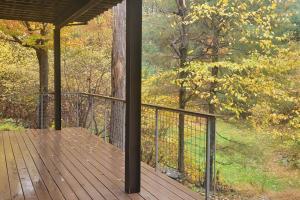 une terrasse couverte avec une clôture sur une terrasse en bois dans l'établissement Double deck treetop art chalet, à Stone Ridge