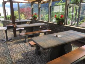 ein Restaurant mit Holztischen und Fenstern mit Blumen in der Unterkunft Hotel Bellavista Cavigliano in Cavigliano