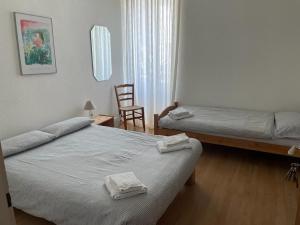 a hotel room with two beds and a chair at Hotel Bellavista Cavigliano in Cavigliano +8 photos