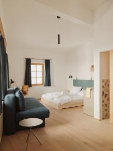 a bedroom with a bed and a couch and a chair at Urban Inn - Wilten 24/7 in Innsbruck