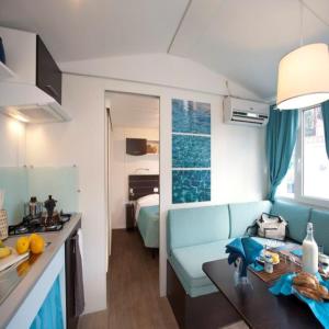a kitchen and a living room with a blue couch at Pet Family Camping Cortina in Senigallia