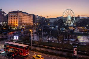 a city with a red double decker bus and a ferris wheel at Budapest Eye- Boutique Suites, by BQA in Budapest