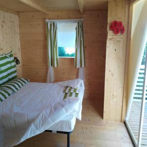 a bedroom in a log cabin with a bed and a window at Pet Family Camping Cortina in Senigallia