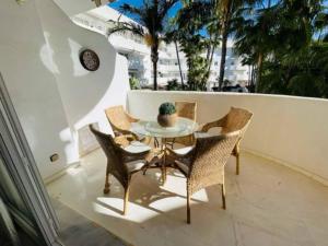 a table and chairs on a balcony with palm trees at Apart Milla de Oro Marbella in Marbella
