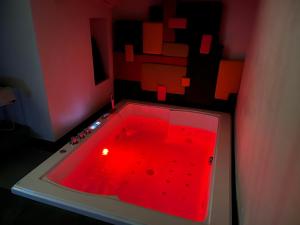 uma banheira vermelha num quarto com luz vermelha em Jacuzzi SUITE con Caminetto La stratodda Appartamento privato vicino al MARE e OSTUNI em San Vito dei Normanni