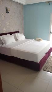 - une chambre dotée d'un grand lit avec des draps et des oreillers blancs dans l'établissement HÔTEL NOAHGARDEN 2, à Cotonou