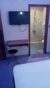a bedroom with a shower and a bench with a television at HÔTEL NOAHGARDEN 2 in Cotonou