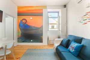 una sala de estar con un sofá azul y una pintura de un barco en Canto da Praça - No coração do centro de Aveiro, en Aveiro