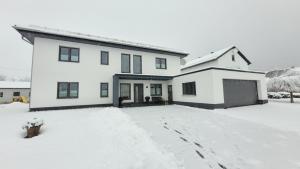 a white house with snow on the driveway at Ring Apartment am Nürburgring in Herresbach