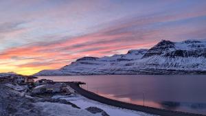 eine Eisenbahnstrecke vor einem schneebedeckten Berg in der Unterkunft Reydarfjordur Apartment in Reyðarfjörður