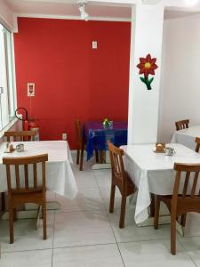 a dining room with two tables and a red wall at Pousada Bem Brasil in Macaé